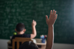 kids raising hand in classroom