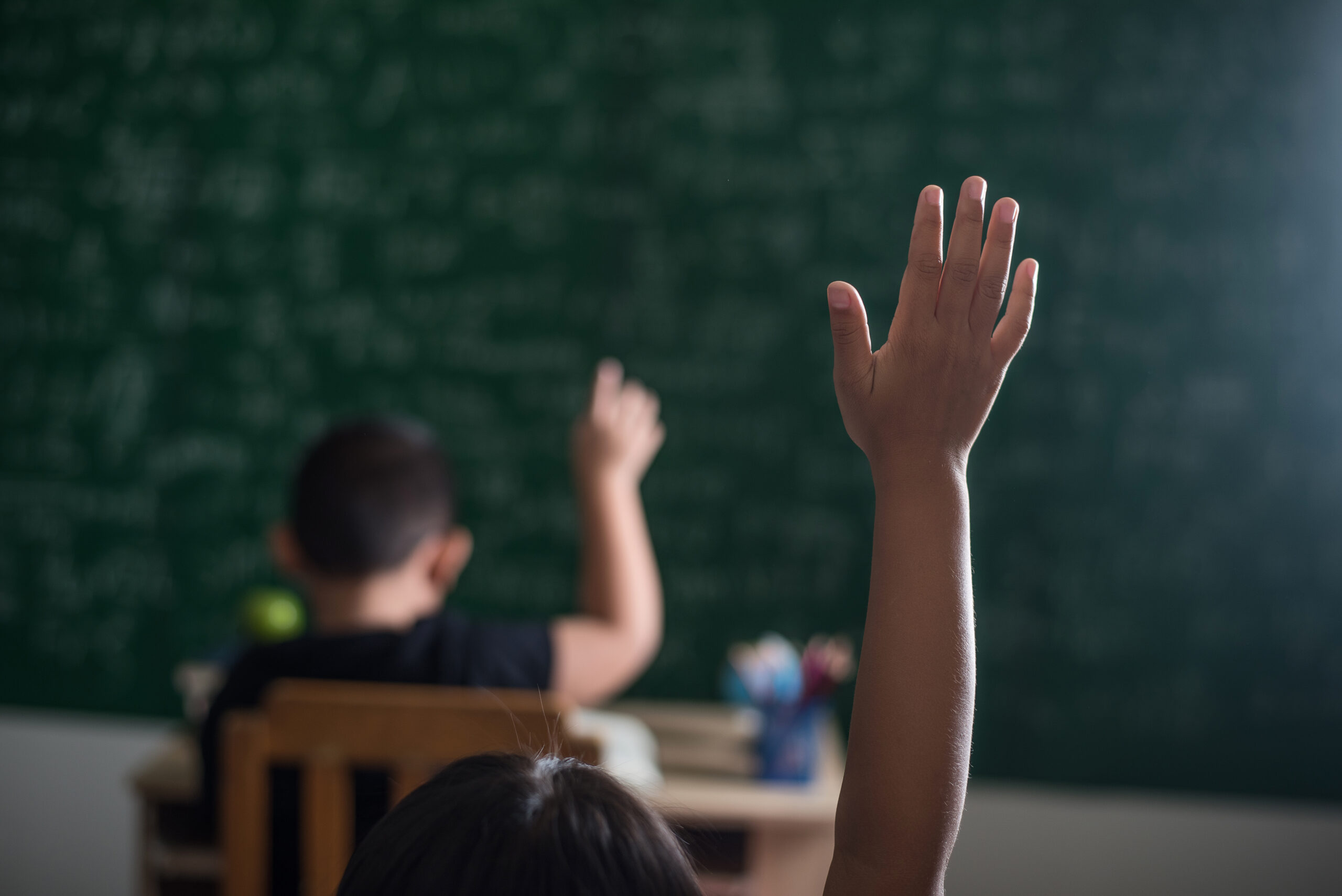 kids raising hand in classroom
